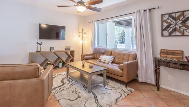 Uma sala de estar com sofá, mesa de centro e ventilador de teto.