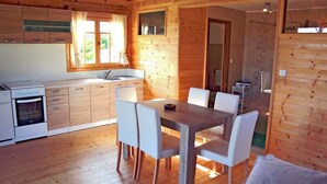 Una cabaña de madera con cocina, comedor y ducha.