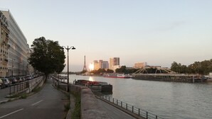 A riverside walkway with a view of the Eiffel Tower in the distance, a bridge, and modern buildings. - one of the best place in Paris, it's historical, diplomatic zone. (Paris)