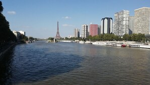 A river with a boat, a prominent tower, and modern buildings along the riverbank. - one of the best place in Paris, it's historical, diplomatic zone. (Paris)