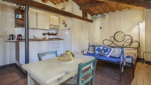 Una habitación con una mesa de comedor, sillas, una cama con cabecera, una zona de cocina y techo de madera.