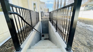 Uma escadaria de concreto com grades de metal preto que leva à entrada de um edifício.