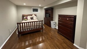 Quarto com cama de madeira, penteadeira e estante embutida para a TV.