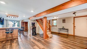 Ein geräumiger Wohnbereich mit einer Holztreppe, einer Küchenbar mit Hockern und einem Essbereich.