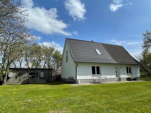 A single-story house with a tiled roof, a front porch, and a small garden area.