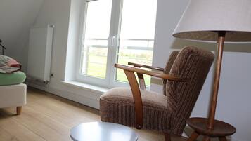 A room with a window, a chair, a small table, and a floor lamp.