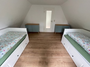 A room with two beds, a door, and a dresser.