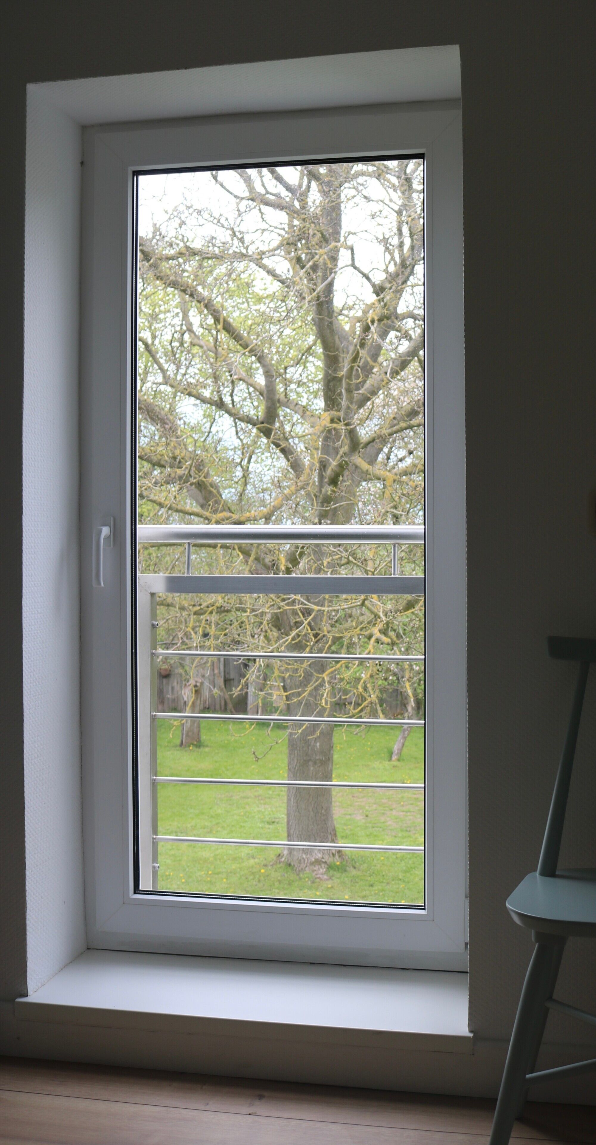 A room with a large window, a door, and a chair.