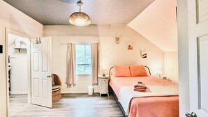 A bedroom with a bed, a window with curtains, a bedside table, and a hanging light fixture. - Soleil Salem- extended stays, free laundry, garden (Salem)