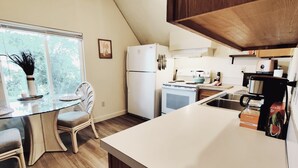 A compact kitchen with a dining area, a refrigerator, a stove, and a coffee maker. - Soleil Salem- extended stays, free laundry, garden (Salem)