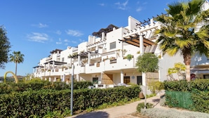 A multi-story hotel with balconies, a paved walkway, and lush greenery. - Sunset Seaview Corner With Pool, Estepona, Spain (Estepona)