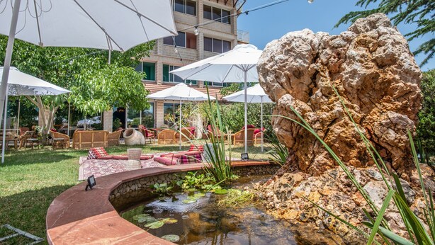 A courtyard with outdoor seating, a rock formation, and a small water feature. - Mantur Metula by Selina (Metula)
