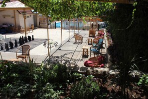 An outdoor patio area with wicker furniture, a pool, and a garden.