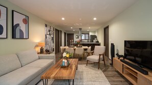 Un salon moderne comprenant un canapé, une table basse, un téléviseur et un coin repas avec des chaises et une table.
