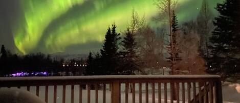 A snowy deck with a view of the northern lights.