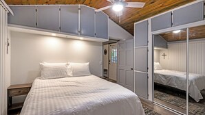 Un dormitorio con cama, ventilador de techo y espejo.
