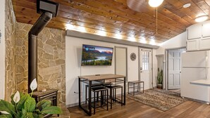 Una cocina moderna con pared de piedra, techo de madera y televisor sobre una barra.