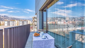 A balcony with a table set for breakfast, a view of the cityscape, and a modern building facade. - ICON H Lugano 506 Suite Business, Lugano, Switzerland (Lugano)