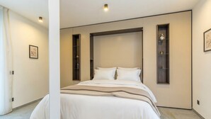 Quarto moderno com cama grande, estantes embutidas e design minimalista.