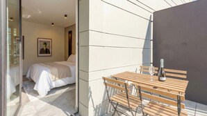 Quarto moderno com cama, mesa de madeira com garrafa e copo, e quadro pendurado na parede.