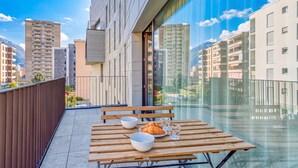 Un balcon avec une table, des chaises et une vue sur les bâtiments de la ville.