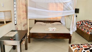 Une chambre à coucher avec un lit en bois, une table de chevet, une chaise et un canapé à motifs.