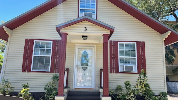 A two-story house with a beige exterior, red trim, and a number '3' above the front door.