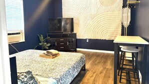 A bedroom with a bed, a TV, a desk, and a chair.