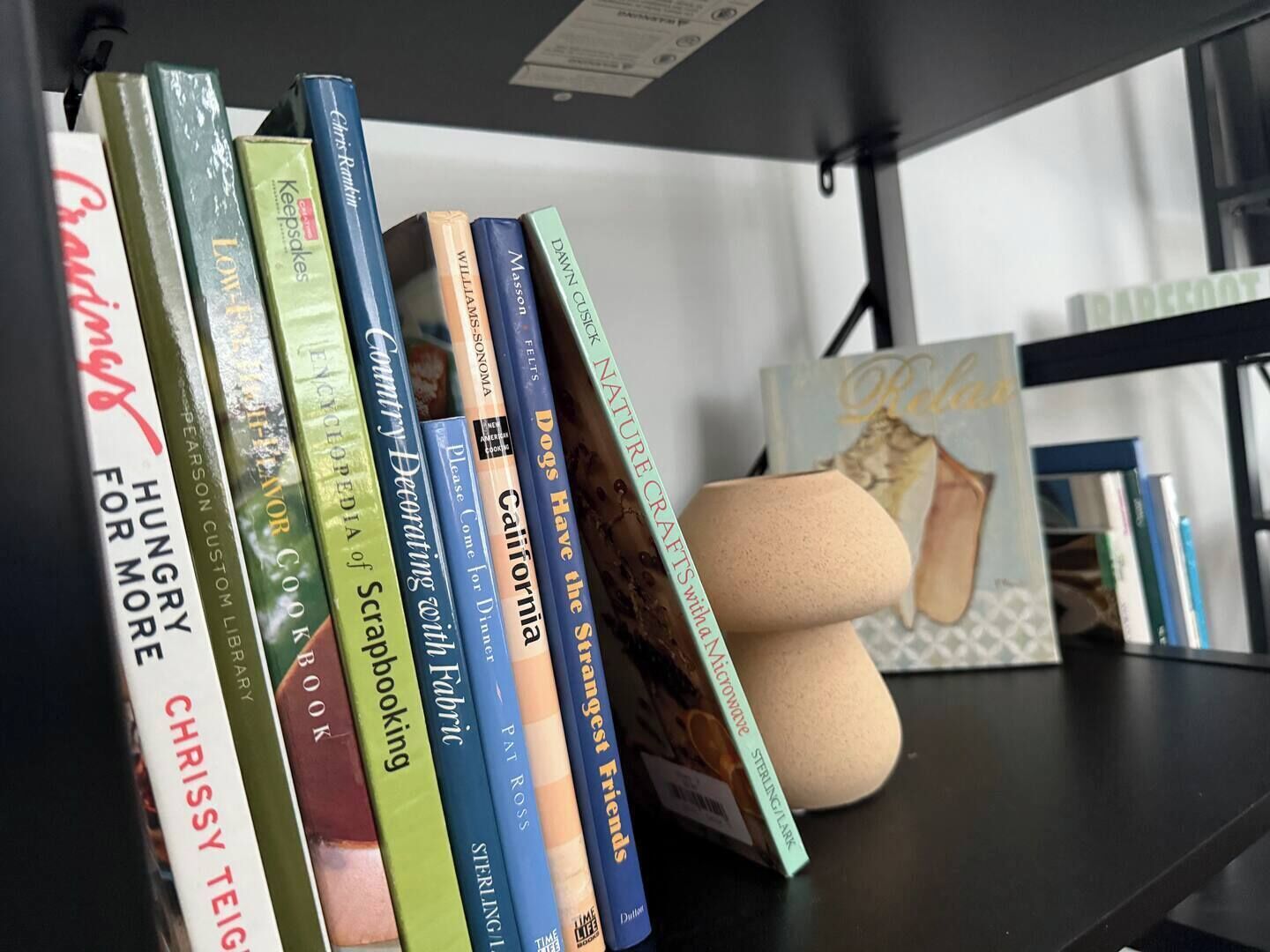 A bookshelf with various books and a decorative item.