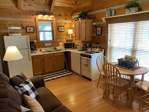 A cozy cabin-style kitchen with wooden cabinets, a refrigerator, a stove, and a dining area with a table and chairs.