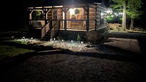 A wooden cabin with a porch and stairs, surrounded by trees and a gravel path. - Beautiful Authentic Log Cabin on Cosby Creek (Cosby)