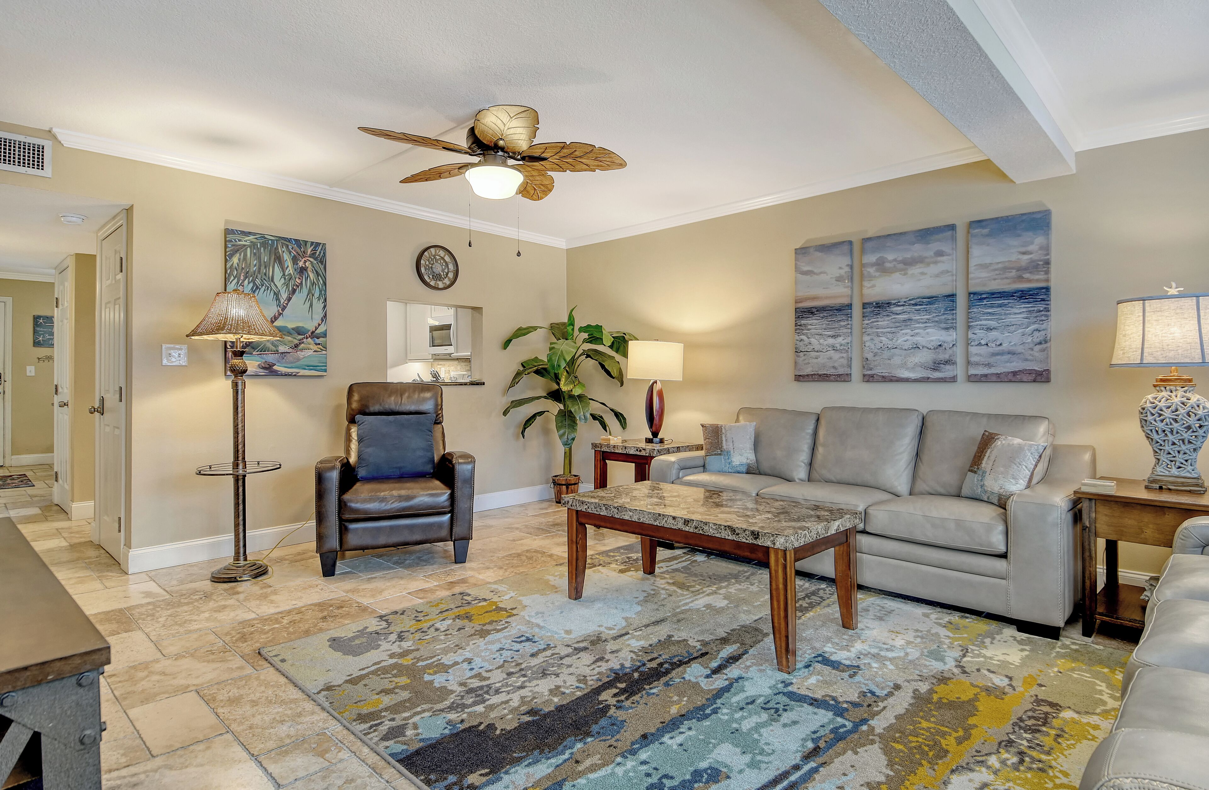A living room with a ceiling fan, a sofa, a coffee table, a chair, a floor lamp, and a potted plant.