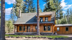 A two-story log cabin with a stone foundation, wooden exterior, and a large front porch. - Timber Cabin in the woods (Cle Elum)