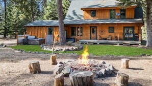 A two-story log cabin with a fire pit in the front yard surrounded by trees. - Timber Cabin in the woods (Cle Elum)