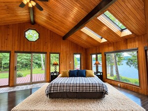 A bedroom with a large bed, wooden walls, and a skylight.
