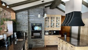 Eine Küche mit Steinwand, Holzschränken, einem eingebauten Backofen und einer schwarzen Dunstabzugshaube.
