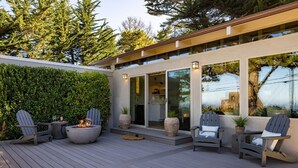 An outdoor deck with Adirondack chairs, a fire pit, and a stone planter. - “Pacific Horizons” hot tub, ocean views, Gateway to Big Sur (Carmel-by-the-Sea)