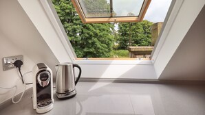 Une fenêtre de toit offrant une vue sur les arbres et une structure en pierre à l’extérieur.