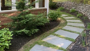 A house with a stone pathway leading to the front door, surrounded by greenery and trees. - Relax villa ,hot tub and New Heated  pool ,7 minutos from the beach  (Hampton Bays)