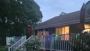 A residential deck with white railings, a stone pathway leading to the house, and a variety of greenery. - Relax villa ,hot tub and New Heated  pool ,7 minutos from the beach  (Hampton Bays)