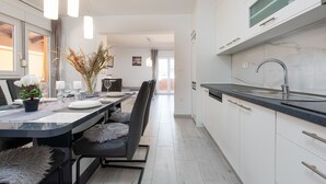 A modern kitchen with white cabinets, a black countertop, and a stainless steel sink. - Villa Jenny (Policnik)