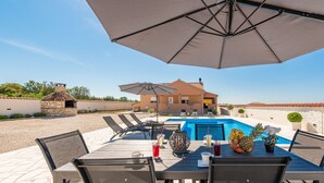 A poolside dining area with a table, chairs, and umbrellas. - Villa Jenny (Policnik)