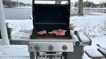Ein Genesis II tragbarer Grill mit vier Steaks, die draußen zubereitet werden.