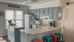 A kitchen with a central island, blue cabinets, and a sign reading "BEACH HOUSE". - ABSOLUTIKI - 3 min walk to beach, Canal with Boat Dock, Outdoor Bar & Shower (Ocean Isle Beach)