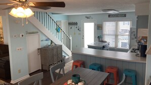 A kitchen with a dining area, a staircase, and a sign that reads "BEACH HOUSE". - ABSOLUTIKI - 3 min walk to beach, Canal with Boat Dock, Outdoor Bar & Shower (Ocean Isle Beach)