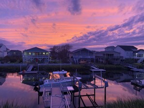 A waterfront property with docked boats, a pier, and houses with balconies overlooking the water.