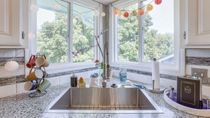 A kitchen with a stainless steel sink, a dish rack, and a bar guide on the counter.