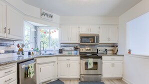 A modern kitchen with white cabinets, stainless steel appliances, and a granite countertop.