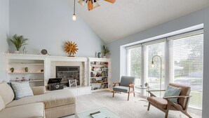 A modern living room with a fireplace, a bookshelf, a sofa, a coffee table, and a chair.