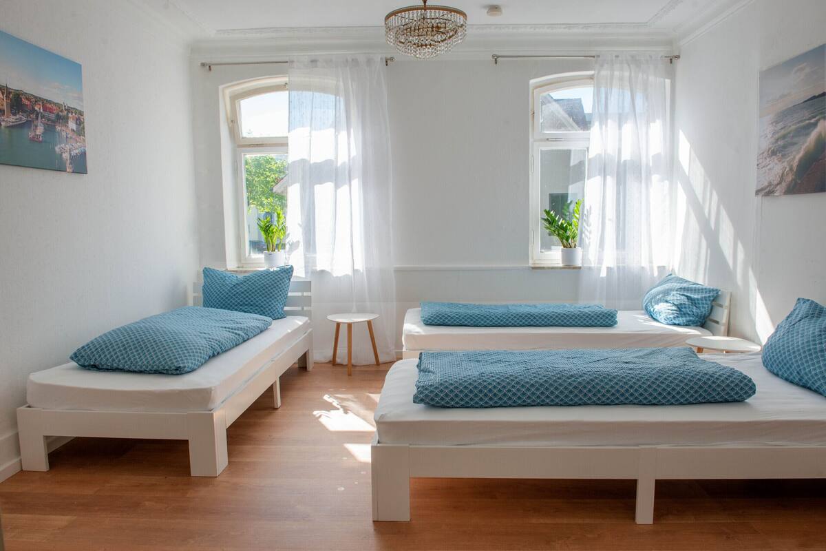 A room with two beds, a small table, and a window with curtains.